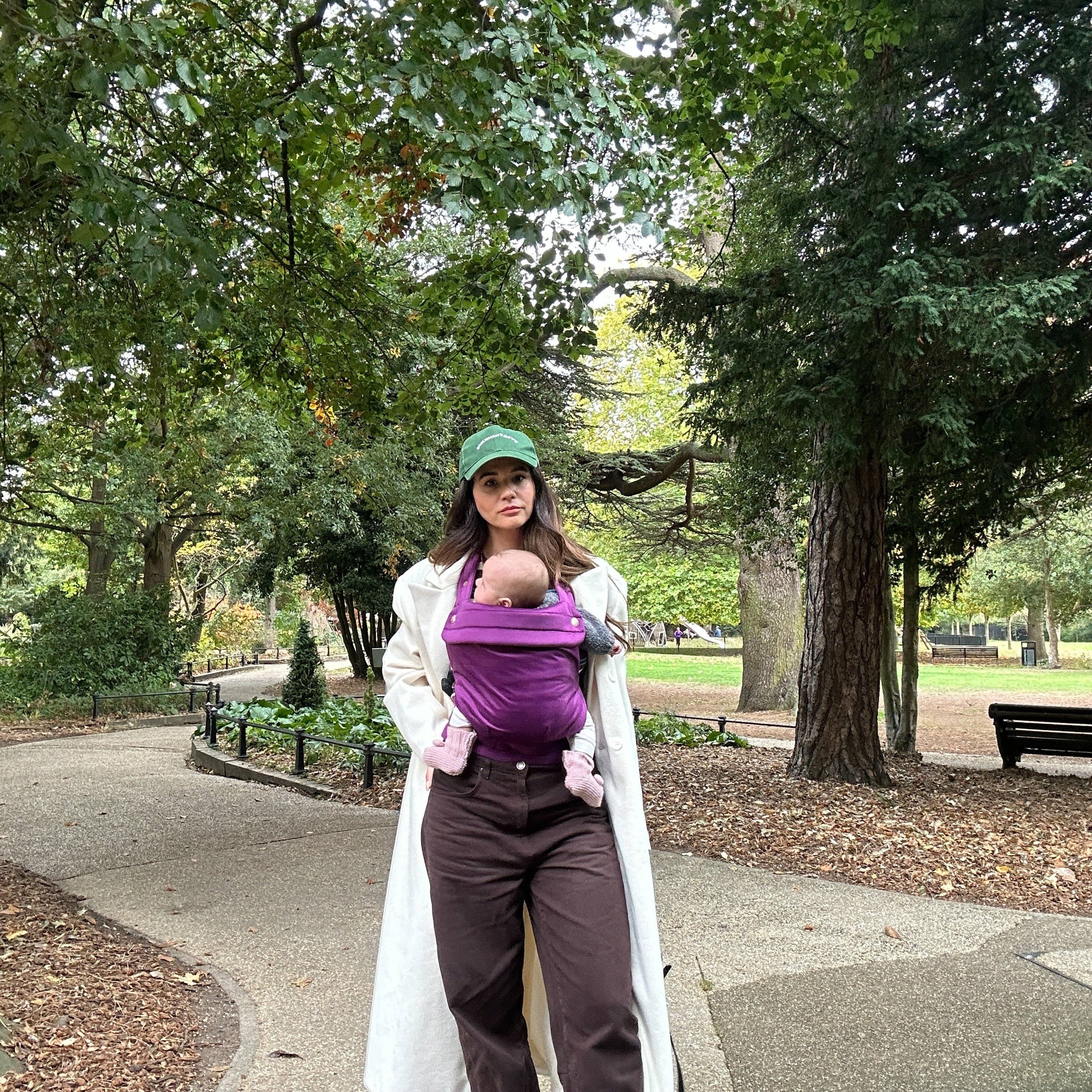 Person walking in a park with a baby in a carrier