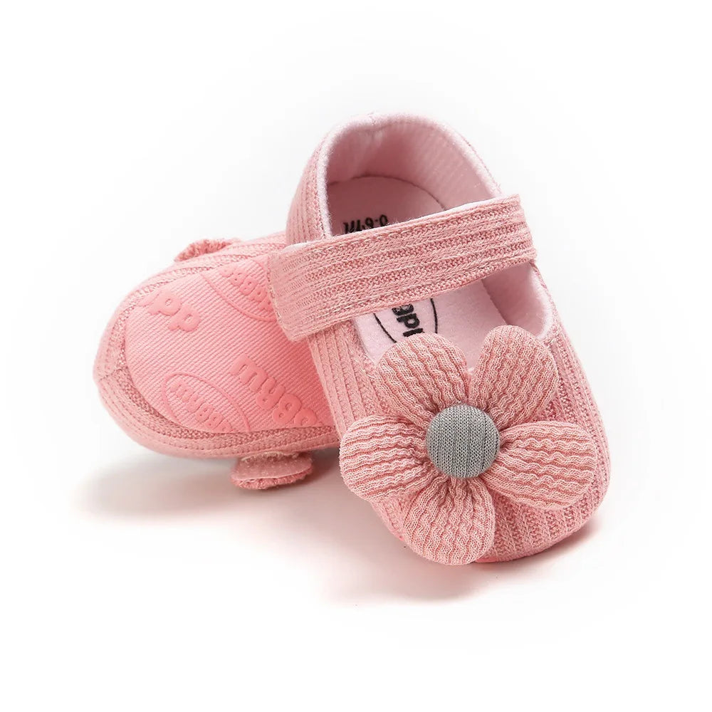 Pink baby shoes with a flower design on a white background