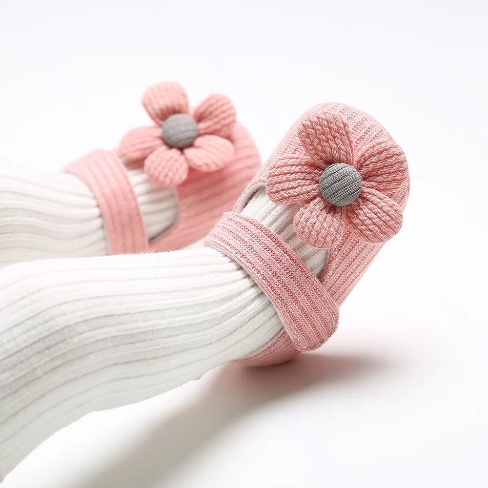 White baby socks with pink flower-shaped booties on a white background