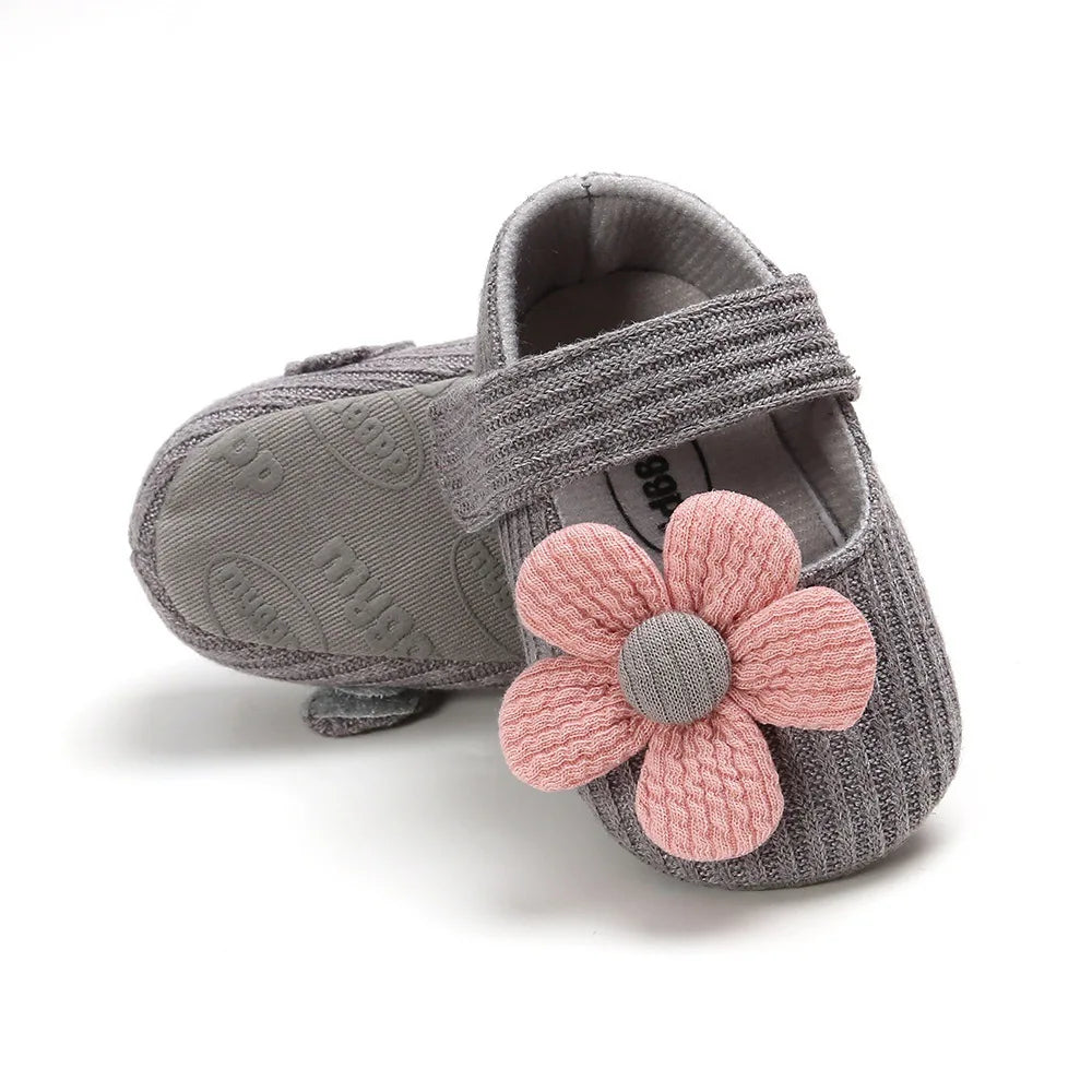 Gray baby shoe with a pink flower on a white background
