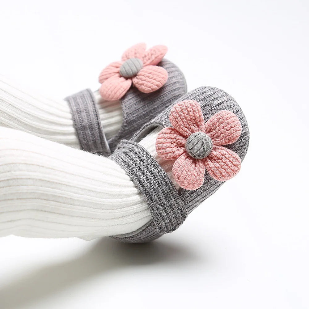 Pair of baby shoes with pink flower designs on a white background